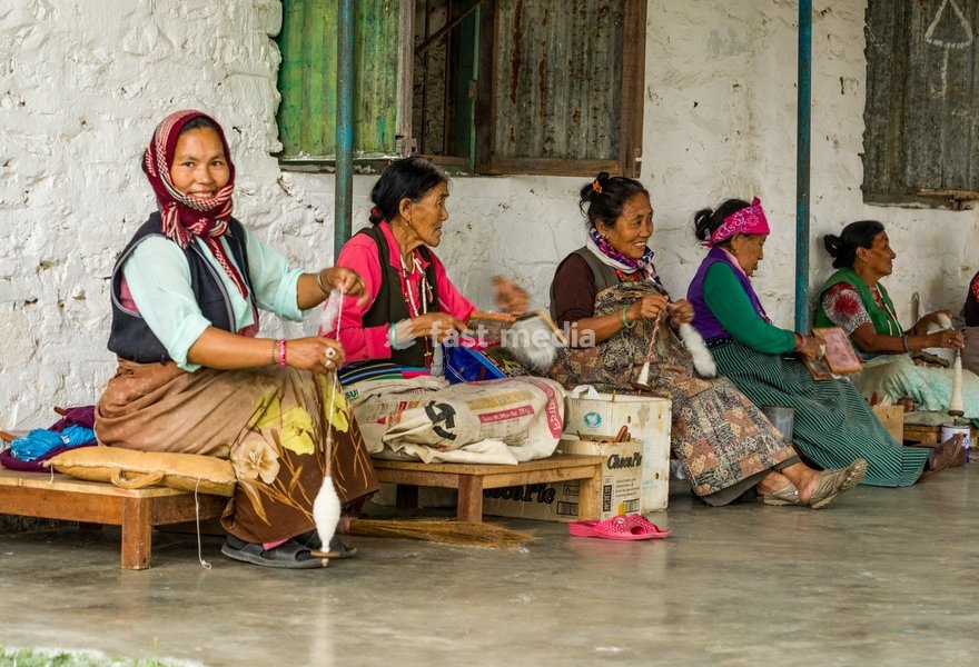 Tibetan refugee women spin wool into yarn by hand for making rugs in a refugee settlement in Pokhara, Nepal