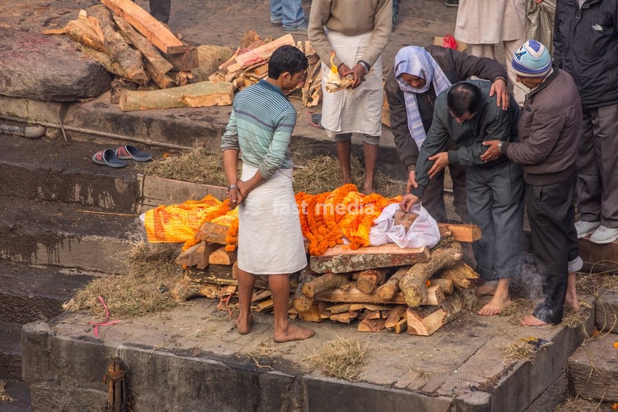 The lead mourner puts rice in the mouth of the deceased in the cremation ceremony at Pashupatinath, Kathmandu, Nepal