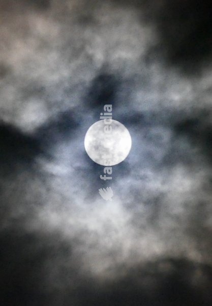 The full Hunters Moon visible at 99.9% surrounded by fast moving thick clouds in the early hours of the morning