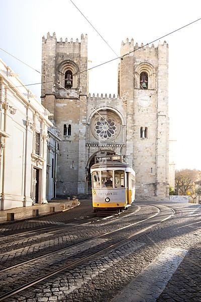 House fronts, narrow streets, alleys and stairs, in a historic old town. beautiful urban place Alfama in the morning with tram, the famous Tram 28 in front of the Cathedral of Lisbon Sé de Lisboa in the capital Lisbon, Portugal