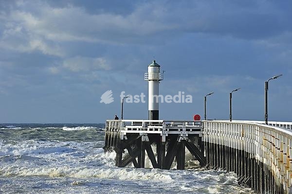 Man looking over the North Sea from wooden pier in stormy weather, Nieuwpoort, Belgium