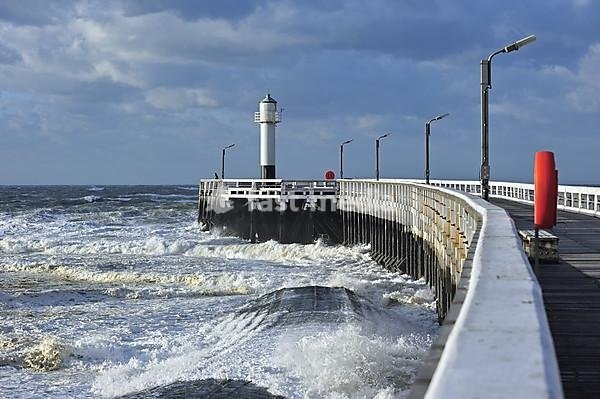 Man looking over the North Sea from wooden pier in stormy weather, Nieuwpoort, Belgium
