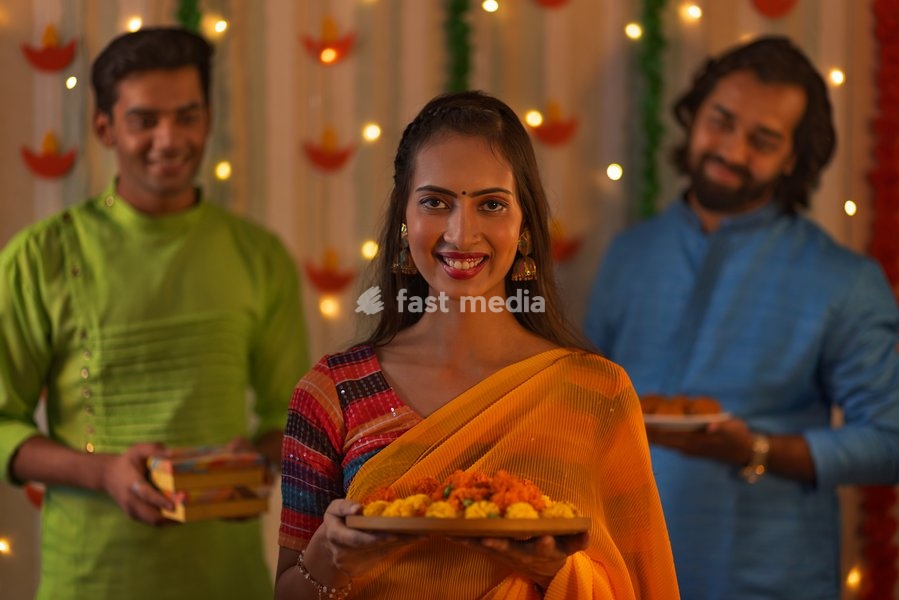 Smiling woman standing with marigold flowers and her friends standing behind during Diwali celebration