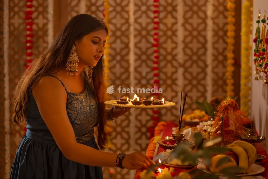 Portrait of Indian woman holding a plate of diyas and worshiping God on Diwali
