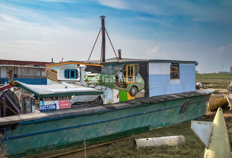 An eccentric houseboat moored at Shoreham by Sea, West Sussex, UK. The houseboat is made from an old barge, a three-wheeled Reliant Robin car and other recycled and upcycled materials