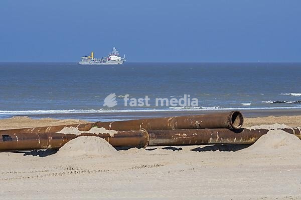 Trailing suction hopper dredger at sea and pipeline for sand replenishment, beach nourishment to reduce storm damage along the Belgian coast