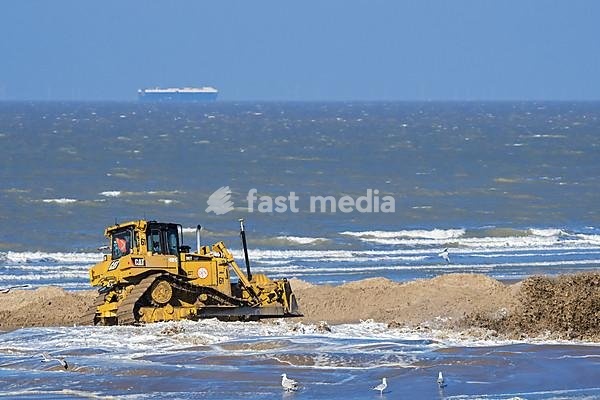 Bulldozer used for sand replenishment, beach nourishment to make wider beaches to reduce storm damage to coastal structures along the Belgian coast