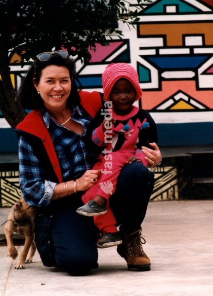 poses with Zinhle and a dog in front of an Ndebele home painted in geometric patterns