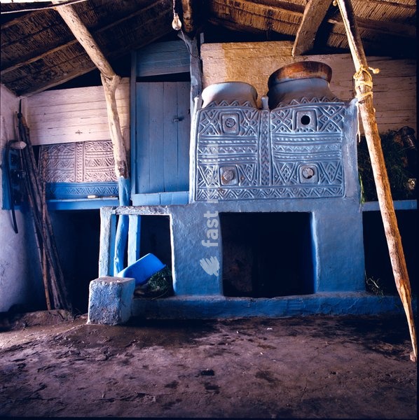 Details from the original home of Ramdane Hales and his family in Ait Mesbah. These extraordinary storage vessels with painted motifs in relief are the work of Ramdane's mother when she was first married. Behind these blue ikoufane is a loft for sleeping and a door that leads to an additional…