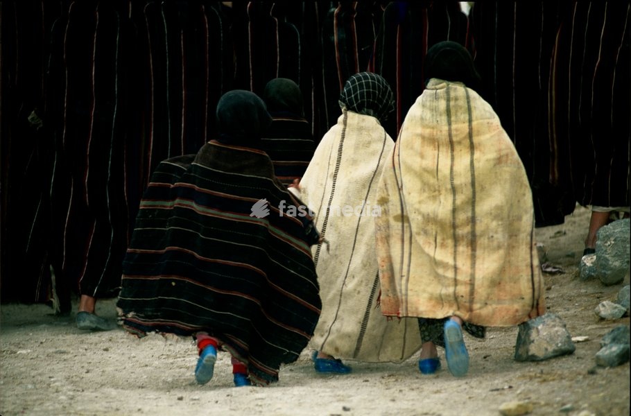 Children wearing handiras, typical of the Ait Brahim tribe, trail their parents on the way to a ceremony in the remote village of Sountate in the High Atlas Mountains, Morocco