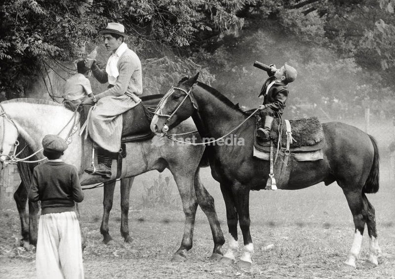 A gaucho allowing his son to drink some beer on his horse. Argentina, November 1957 SPECIAL FEE - CONTACT US FOR NOT EDITORIAL USAGE
