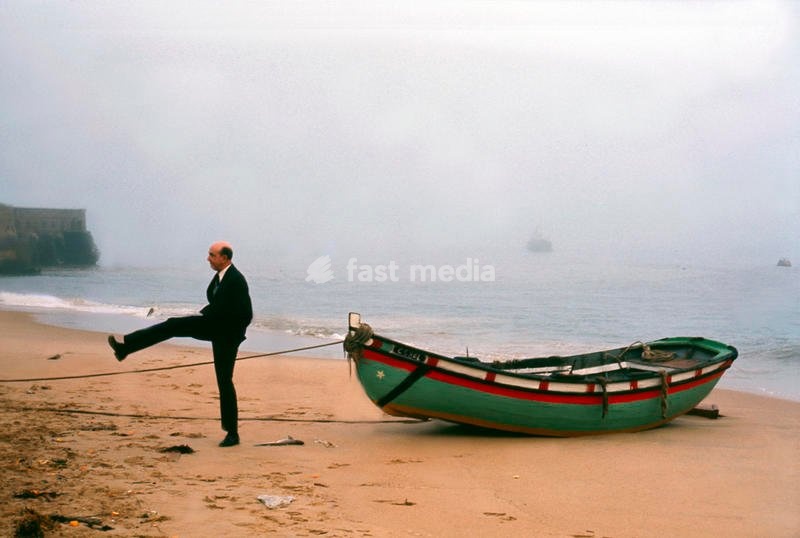 King Umberto II of Italy on the beach, crosses the rope holding a boat tied to the shoreline. Cascais, Portugal, 1965. SPECIAL FEE - CONTACT US FOR NOT EDITORIAL USAGE