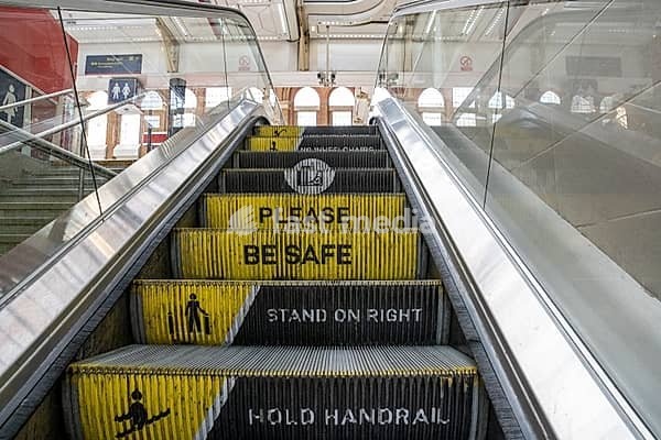 Escalator at the train station with step riser messaging, please be safe, stand on right and hold handrail. Safety sign and warning